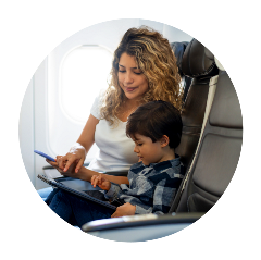 Mom and young son on airplane looking at phone and tablet